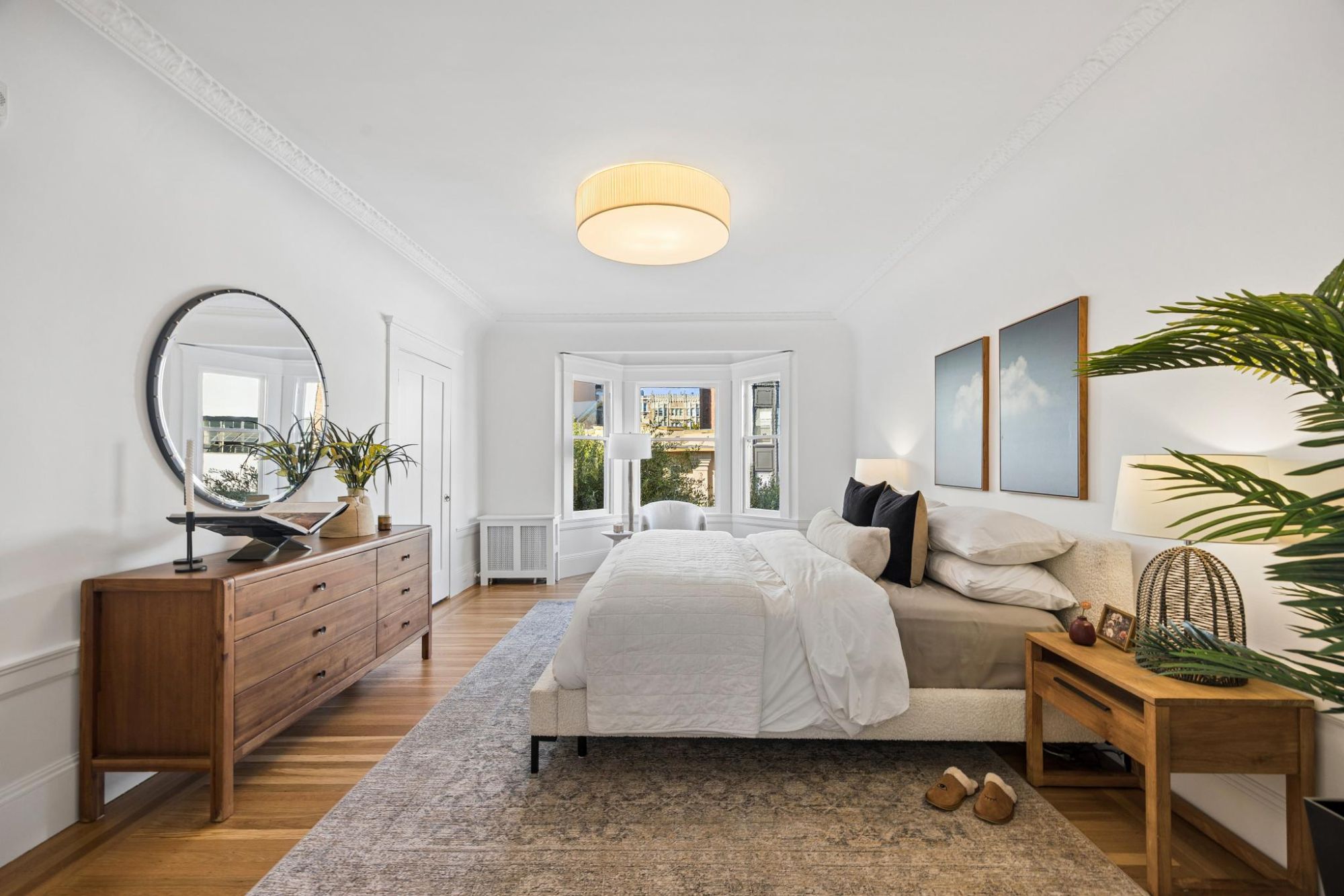 Bedroom with a three-window bay, a reading chair, a queen bed, and a wood dresser
